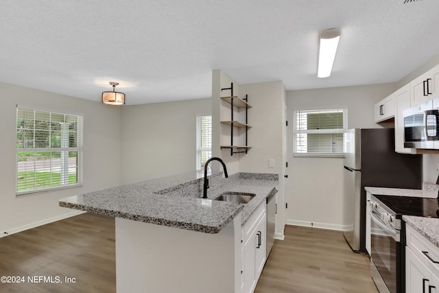 kitchen featuring light stone counters, sink, white cabinets, light hardwood / wood-style flooring, and appliances with stainless steel finishes