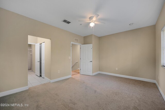 unfurnished bedroom with ceiling fan, ensuite bathroom, and light carpet