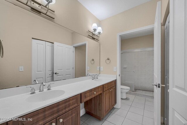 bathroom with vanity, toilet, a tile shower, and tile patterned flooring