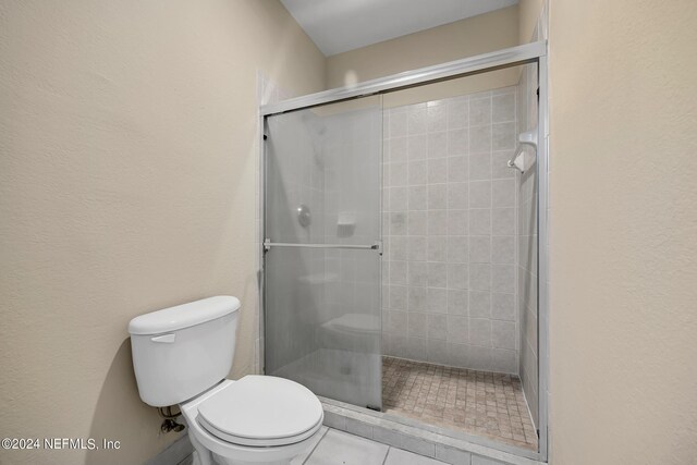 bathroom featuring toilet, an enclosed shower, and tile patterned flooring