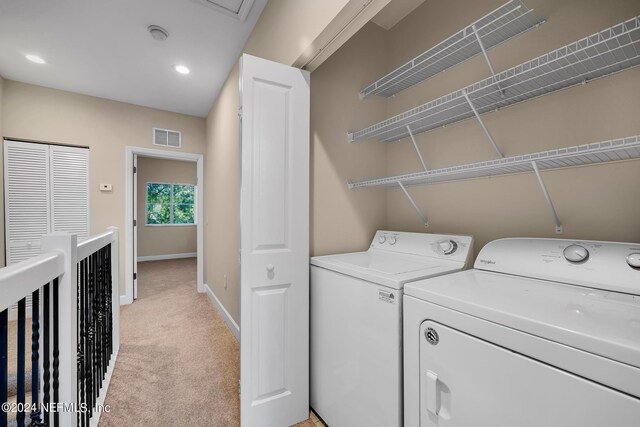 clothes washing area with light colored carpet and washer and clothes dryer