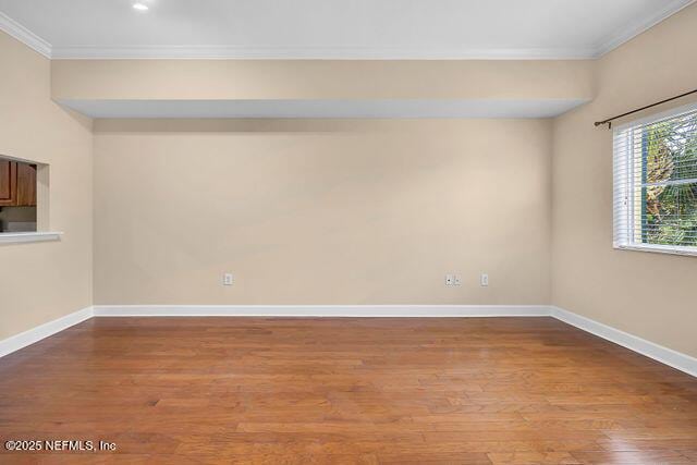 unfurnished room featuring crown molding, wood finished floors, and baseboards