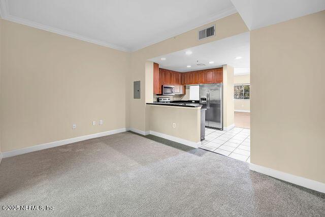 kitchen featuring stainless steel appliances, baseboards, ornamental molding, a peninsula, and open floor plan