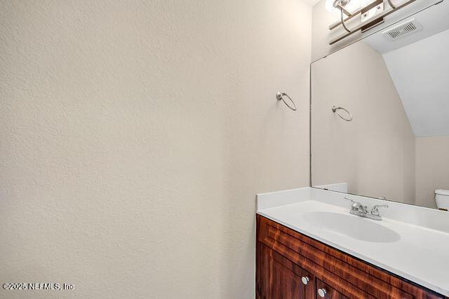 half bath with vaulted ceiling and vanity