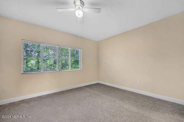 carpeted empty room featuring baseboards and a ceiling fan