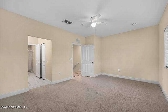 unfurnished bedroom with light carpet, baseboards, ensuite bath, and ceiling fan