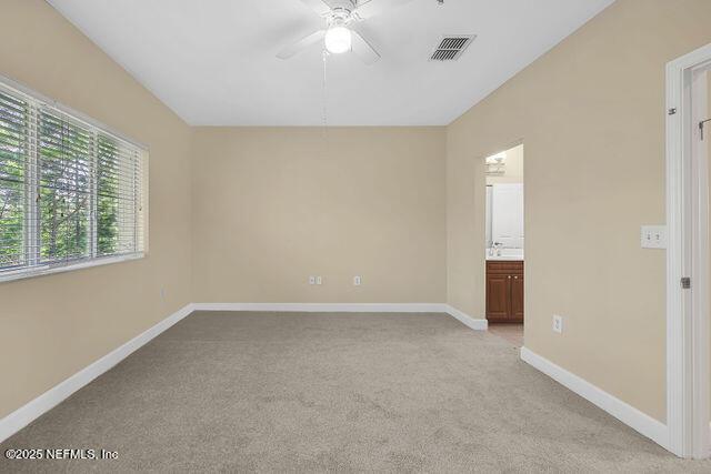 spare room featuring light carpet, ceiling fan, and baseboards