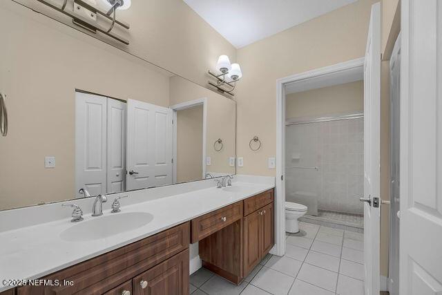 full bathroom with tile patterned flooring, toilet, double vanity, and a shower