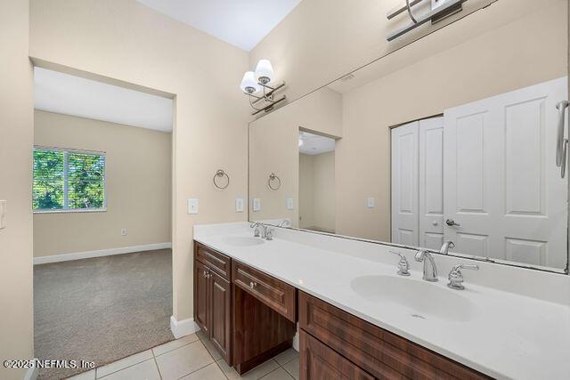 full bath with double vanity, tile patterned floors, and baseboards