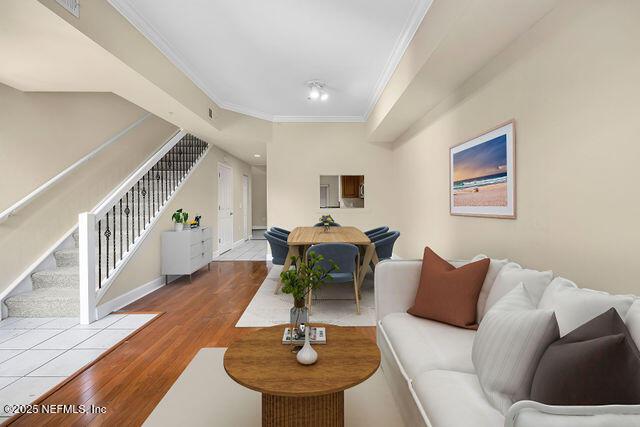 living area with crown molding, stairs, wood finished floors, and baseboards