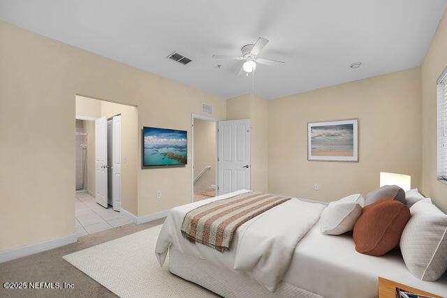 bedroom featuring light carpet, baseboards, connected bathroom, a ceiling fan, and light tile patterned floors