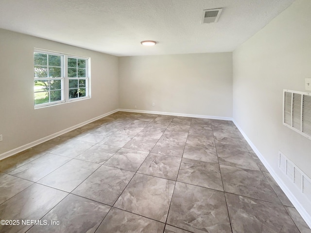 spare room with a textured ceiling, visible vents, and baseboards