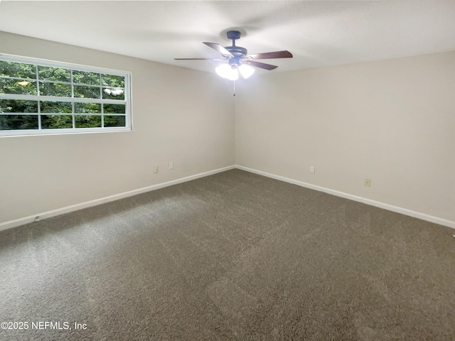 unfurnished room with a ceiling fan, dark carpet, and baseboards