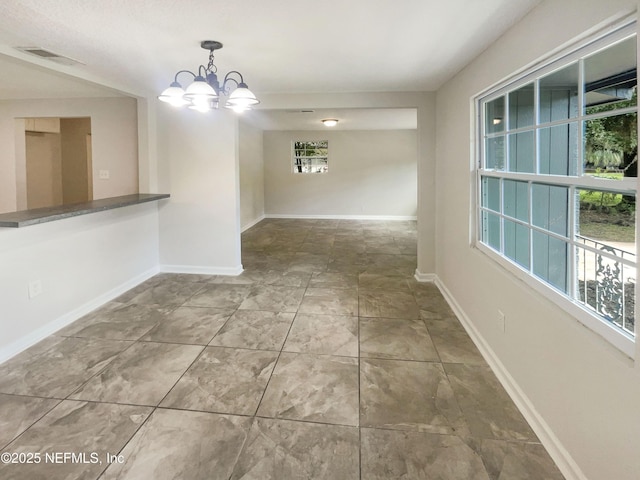 unfurnished dining area featuring a chandelier, tile patterned floors, visible vents, and baseboards