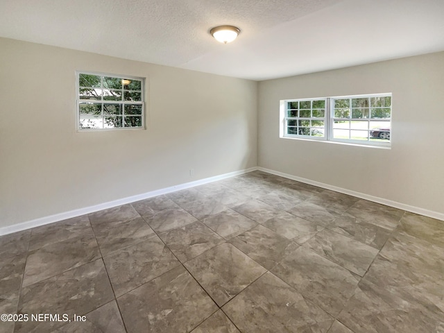 spare room featuring baseboards and a textured ceiling