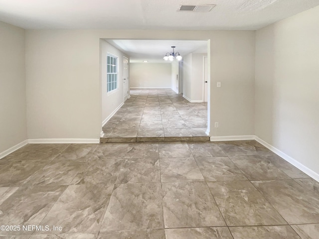 empty room featuring visible vents, baseboards, and an inviting chandelier