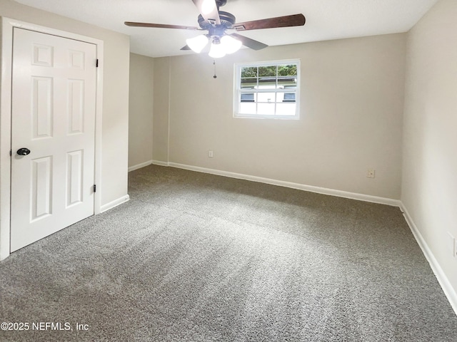 carpeted spare room featuring baseboards and a ceiling fan