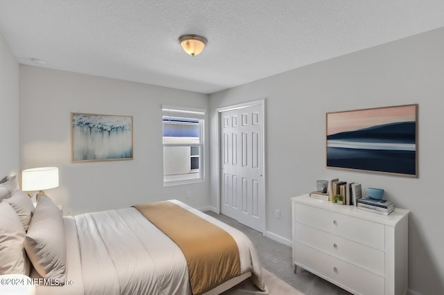 carpeted bedroom featuring a textured ceiling and a closet