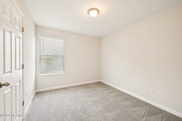 carpeted empty room with a textured ceiling