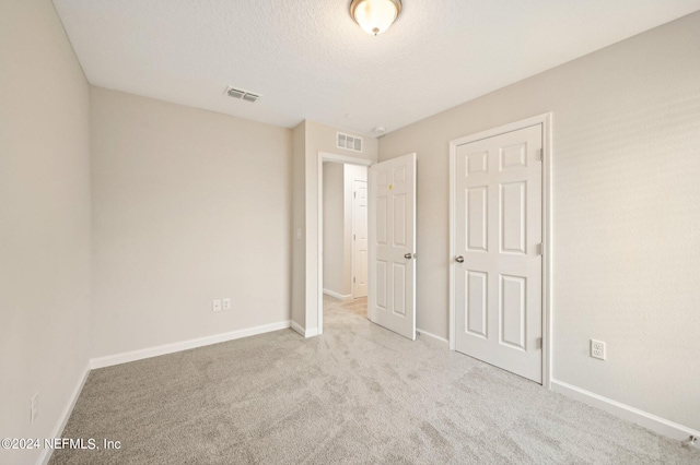 unfurnished bedroom featuring light carpet and a textured ceiling