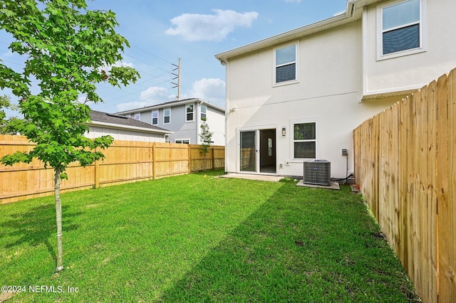 back of property with a yard and central AC unit