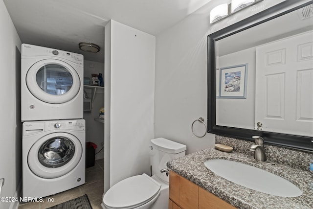 bathroom featuring tile patterned floors, vanity, toilet, and stacked washer / dryer