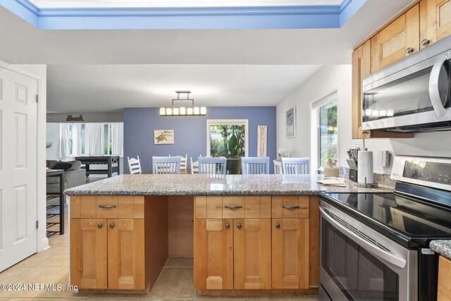 kitchen with light tile patterned floors, light stone counters, stainless steel appliances, and pendant lighting