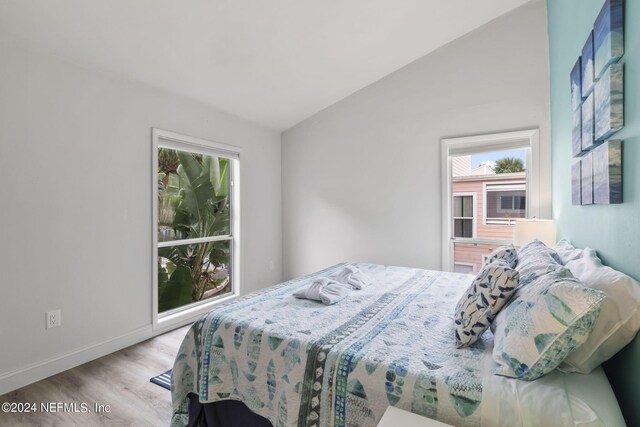 bedroom with light wood-type flooring and vaulted ceiling