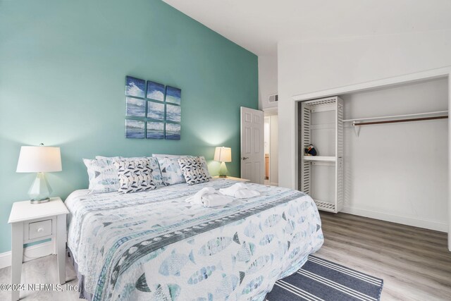 bedroom featuring lofted ceiling, a closet, and hardwood / wood-style floors