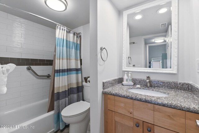 full bathroom featuring toilet, shower / tub combo with curtain, and vanity