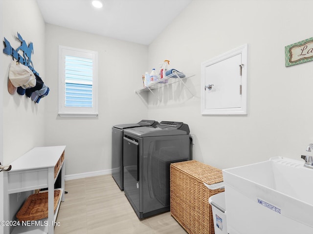 washroom with laundry area, a sink, baseboards, washer and dryer, and light floors