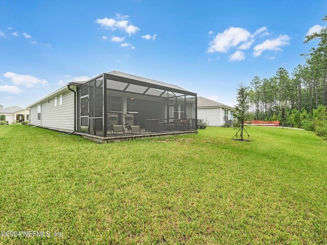 rear view of property with glass enclosure and a lawn