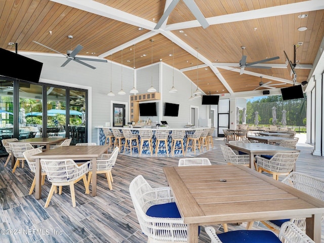 wooden terrace with a bar, ceiling fan, and outdoor dining space