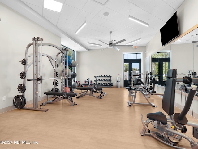 gym featuring baseboards, a ceiling fan, a drop ceiling, wood finished floors, and french doors