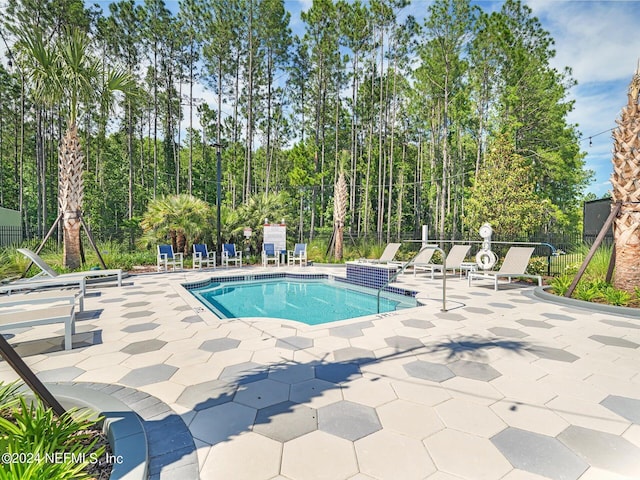 community pool with a patio area and fence