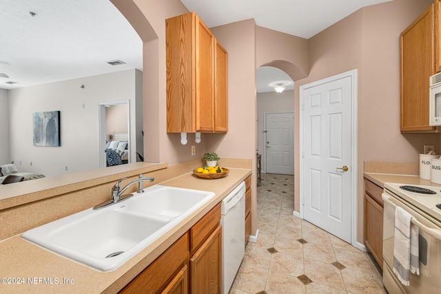 kitchen with light tile patterned floors, white appliances, and sink