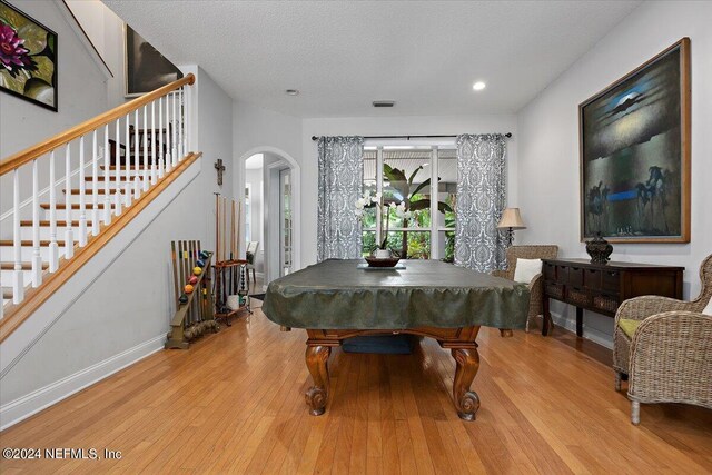 recreation room with billiards, light wood-type flooring, and a textured ceiling