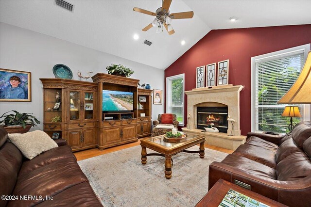 living room featuring a fireplace, vaulted ceiling, light hardwood / wood-style flooring, and ceiling fan