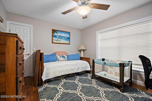 bedroom with a textured ceiling, ceiling fan, and hardwood / wood-style floors