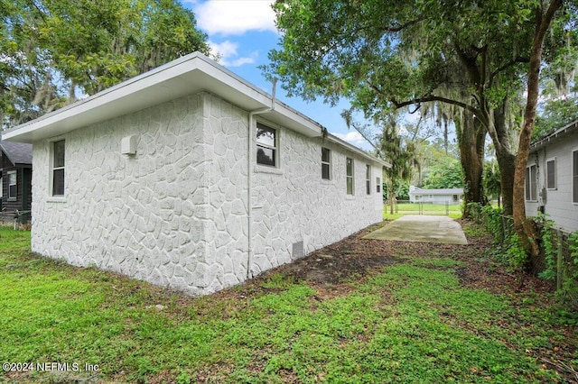 view of property exterior featuring a lawn and a patio