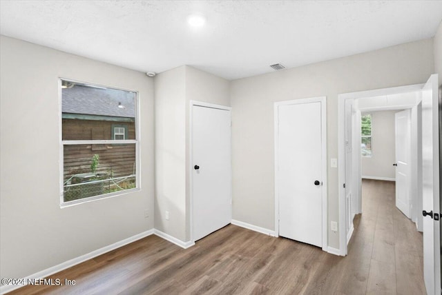 unfurnished bedroom featuring multiple windows and hardwood / wood-style flooring