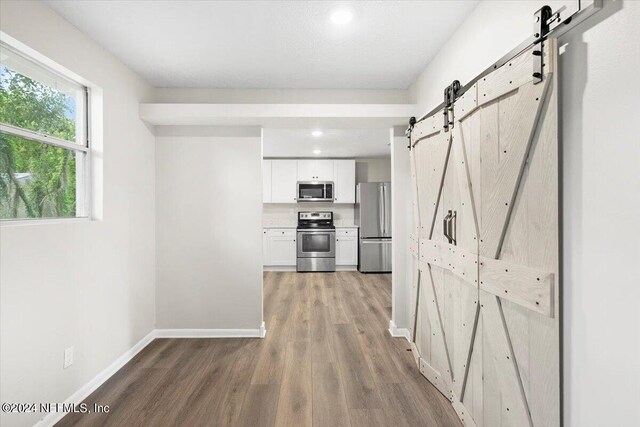 corridor featuring a barn door and dark hardwood / wood-style flooring