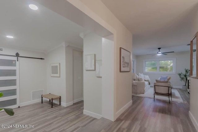 corridor with a barn door and light hardwood / wood-style floors