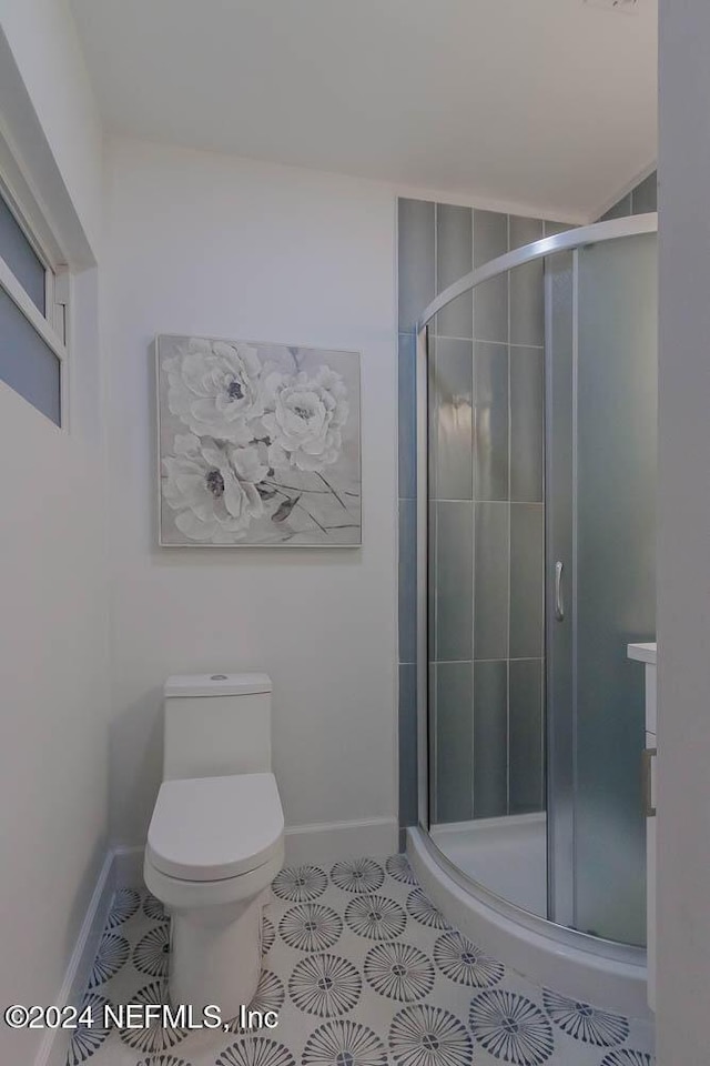 bathroom with tile patterned flooring, toilet, and a shower with shower door