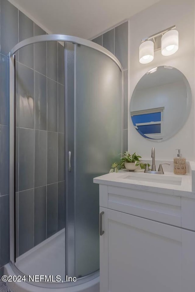 bathroom featuring a shower with door and vanity