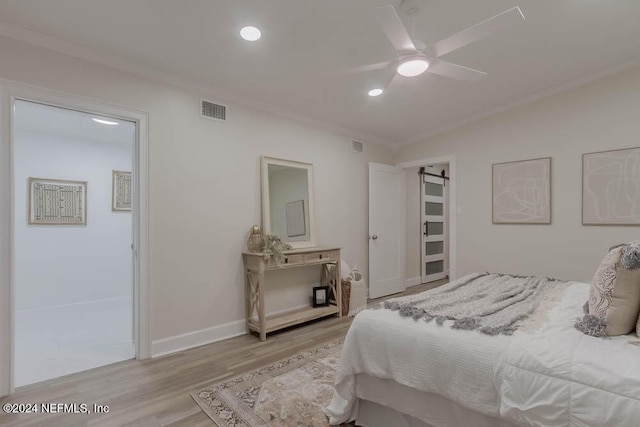 bedroom with vaulted ceiling, ceiling fan, crown molding, a barn door, and light hardwood / wood-style floors