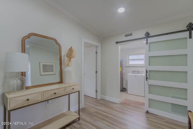 hallway featuring light wood-type flooring, a barn door, and ornamental molding