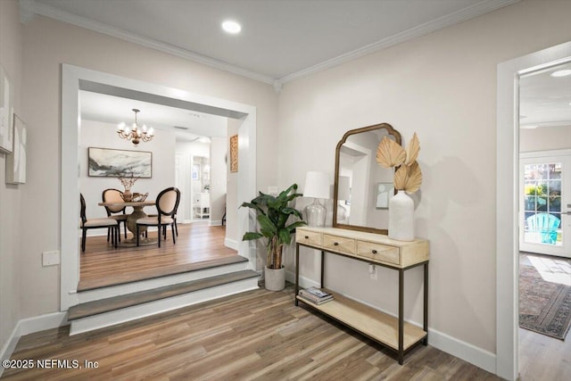 hall with crown molding, an inviting chandelier, and hardwood / wood-style floors