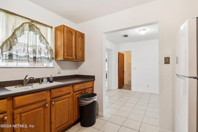 kitchen with sink, light tile patterned floors, and white refrigerator