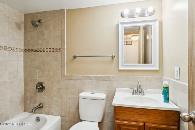 full bathroom with tile walls, vanity, and toilet